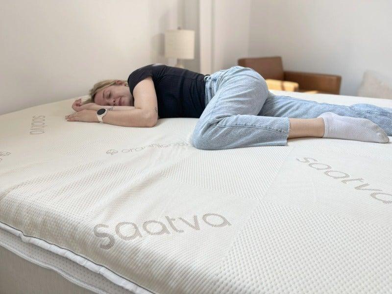A woman lies on her side on the Saatva topper