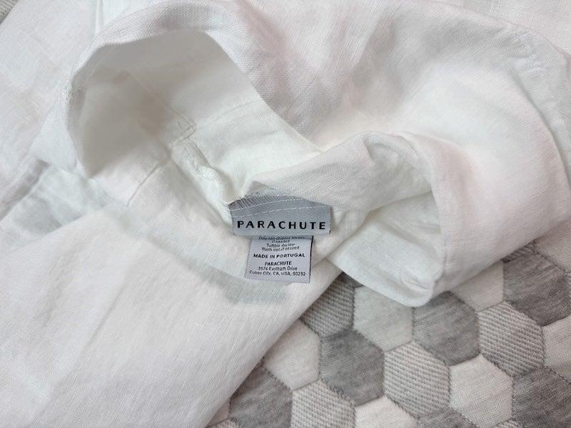 An empty white linen pillowcase with a Parachute label showing