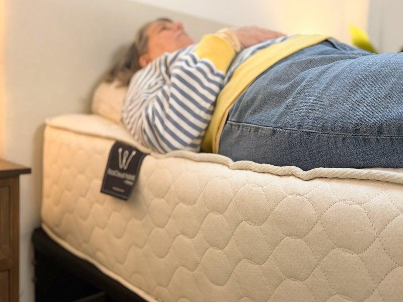 A woman lies on her back near the edge of the WinkBed EcoCloud mattress