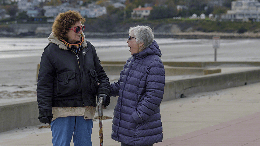 Two older women friends outside with one gasping at what the other just said