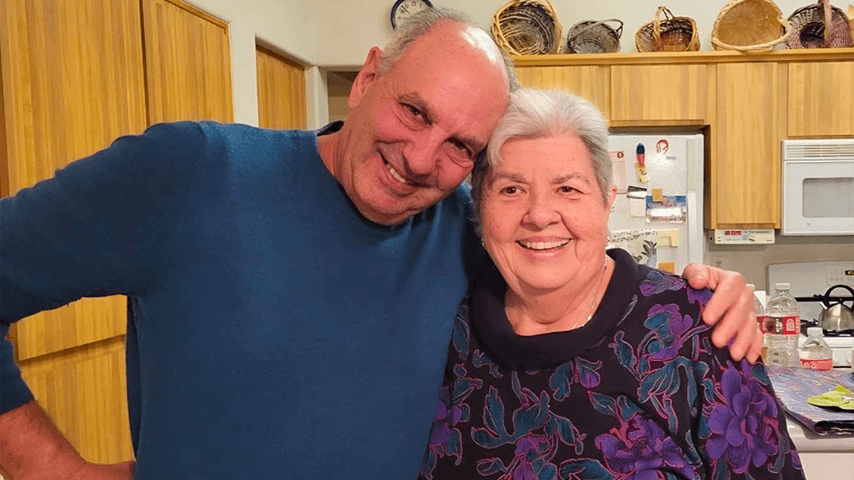 smiling older man and woman embracing in kitchen