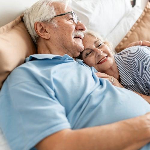 A man and a woman cuddle together in bed
