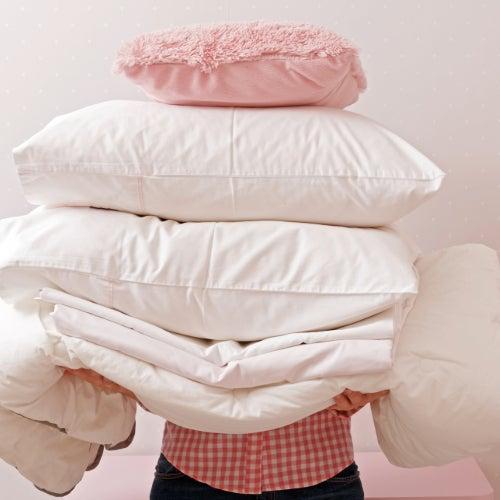 A person holding a pile of bedding