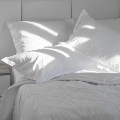 A bed with white pillows and a blanket