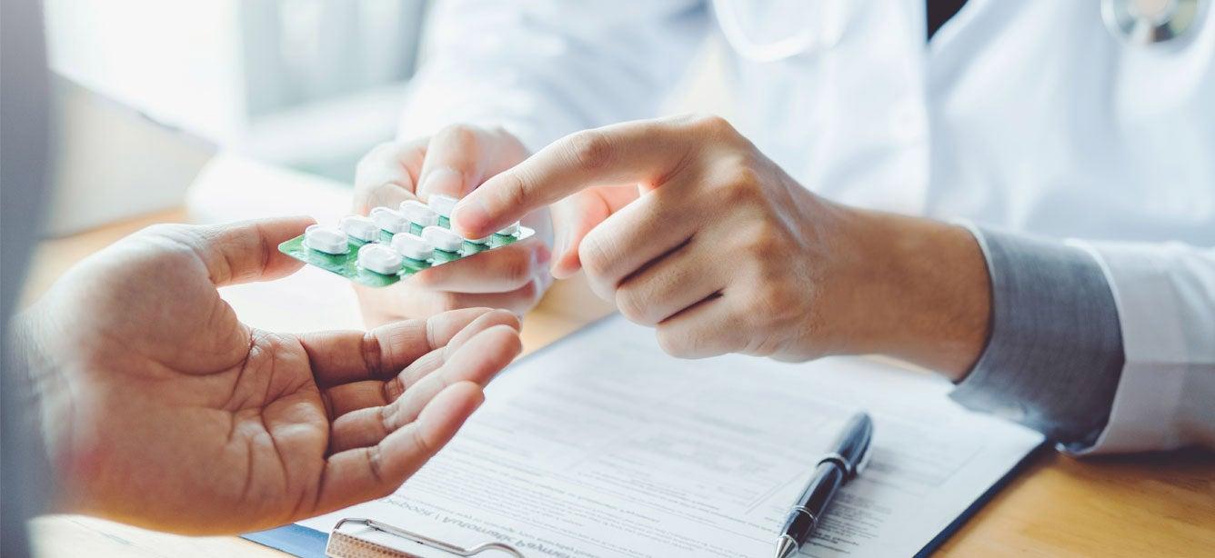 A doctor provides a recommended prescription to his male patient in the hospital.