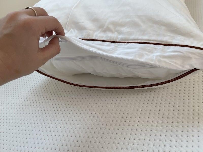 A hand holding the Saatva Latex pillow open to see its interior.