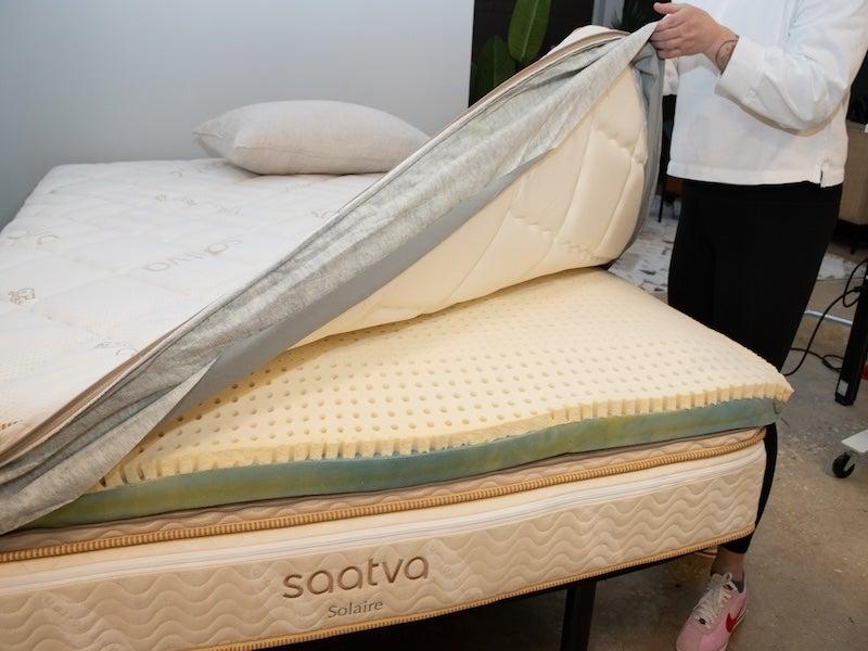 The quilted topper of the Saatva Solaire is lifted to reveal the adjustable comfort layers inside