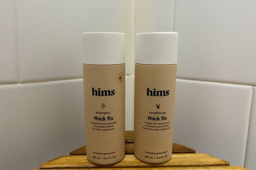 Hims thick fix shampoo and conditioner on a shelf in the corner of a shower