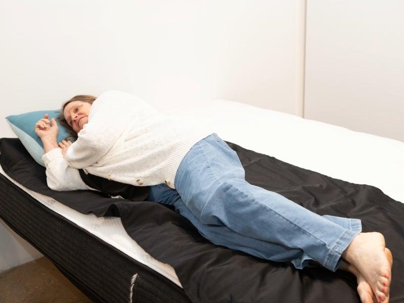 A woman lies on her side on a pressure map on top of a mattress