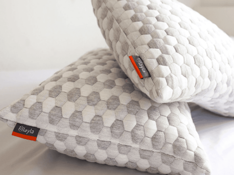 Two pillows with gray and white hexagonal patterned fabric and black and red tags reading “Layla”