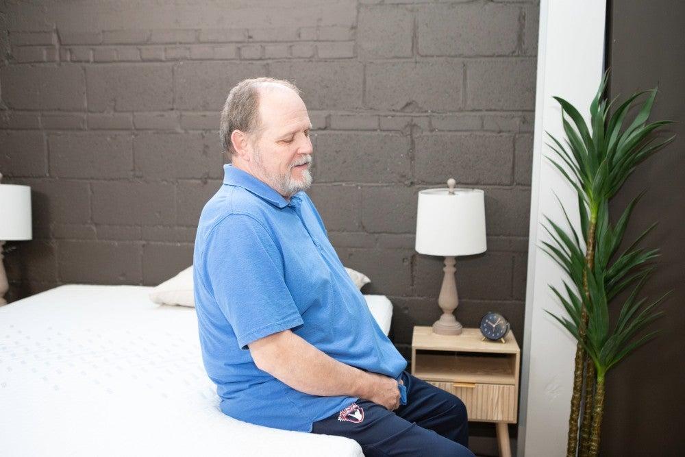 A man testing the seated edge support of the Nectar Memory Foam mattress