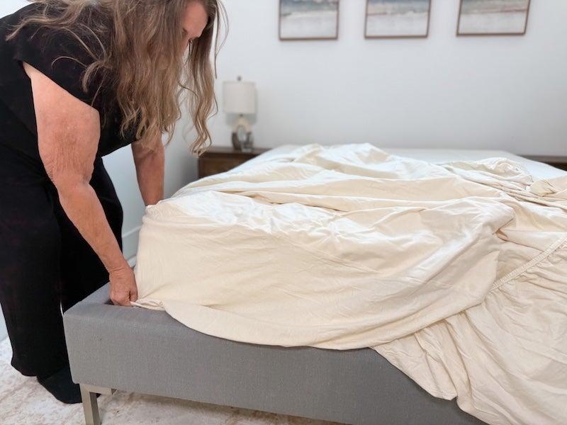 A woman puts the Birch Waterproof Mattress Protector on a mattress.