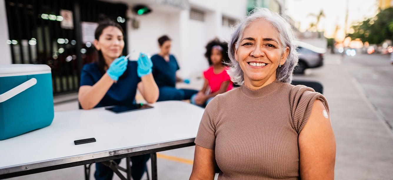 Woman smiles at camera after getting a vaccine.