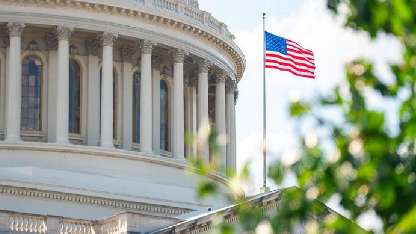 An American flag waves in front of the U.S. Capitol Building.