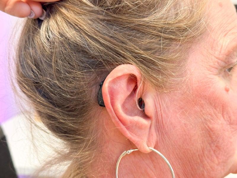 A closeup picture of a woman's ear with the Soundbright Discover hearing aid inserted