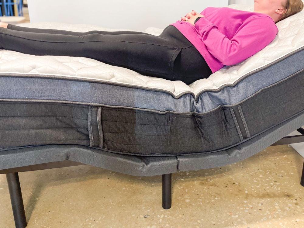 A woman lying on the Helix Midnight Luxe mattress on an adjustable bed with her head and legs slightly raised