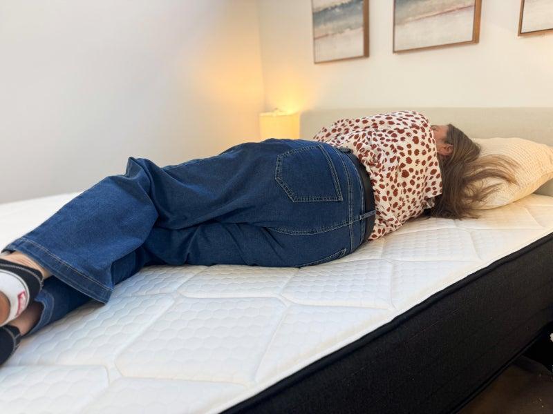 A woman lying on her side on the Plank Firm Luxe mattress