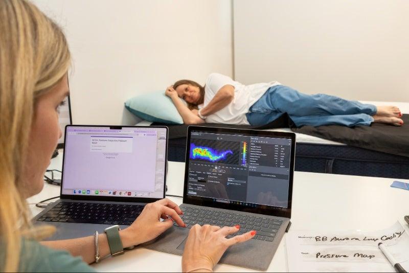 A woman lying on her side on a pressure mat on the Brooklyn Bedding Aurora Luxe mattress as a reading is taken.
