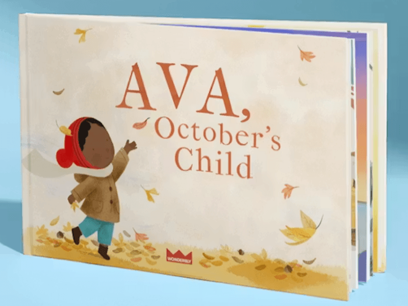 Children's storybook with illustration of child catching a falling leaf and title “Ava, October’s Child”