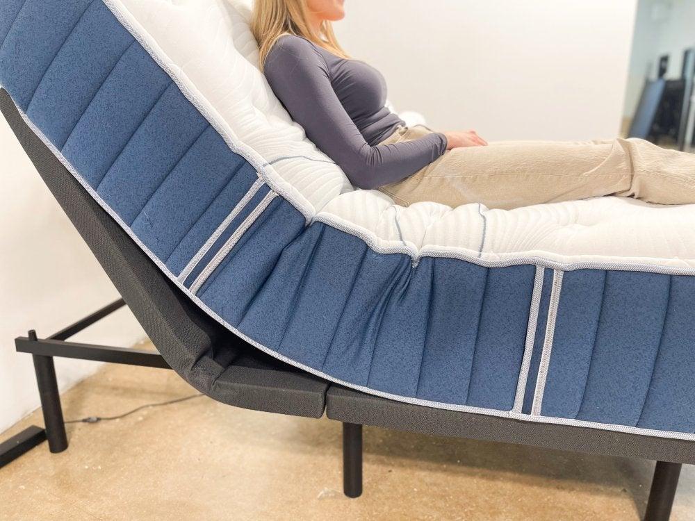 A woman resting on the Bear Elite mattress on an adjustable frame