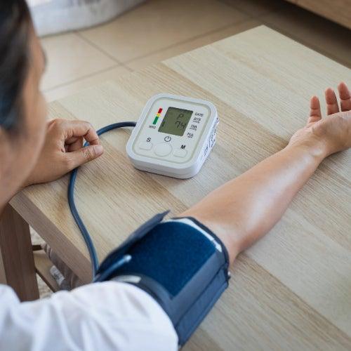A woman checking blood pressure and heart rate with a home blood pressure monitor