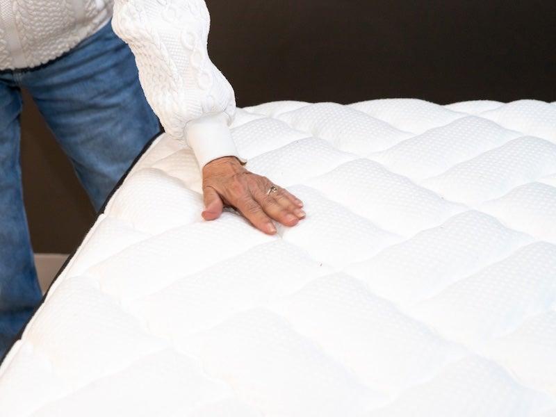 A tester presses down on the top of the Nectar Premier memory foam mattress with her hand