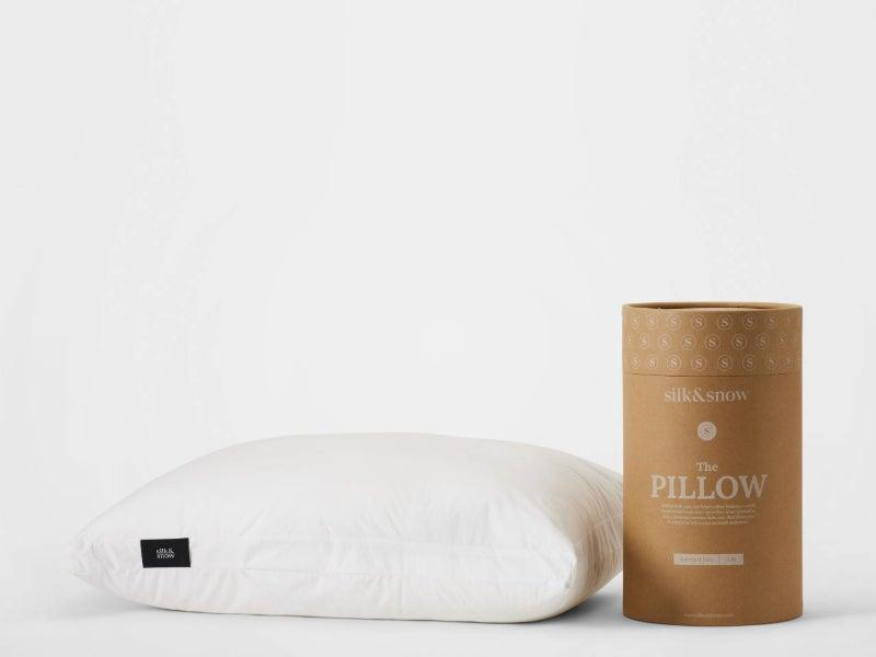 A white Silk & Snow adjustable pillow against a white background with the cardboard tube it arrives in