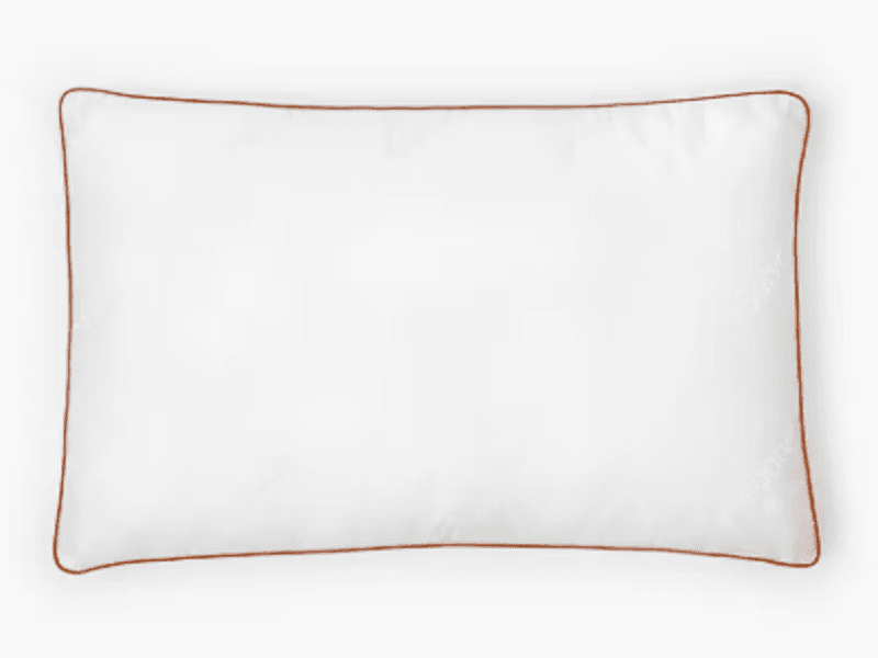 A rectangular, white Saatva latex pillow with dark gold trim