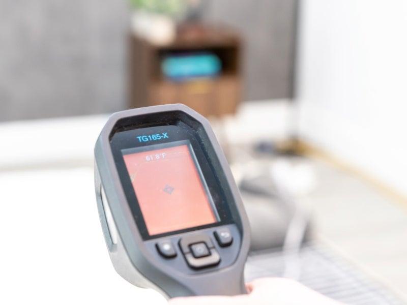 A temperature gun shows a screen that reads 61.8 degrees F