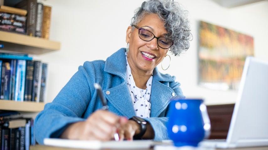 Woman smiles while writing with a pen.