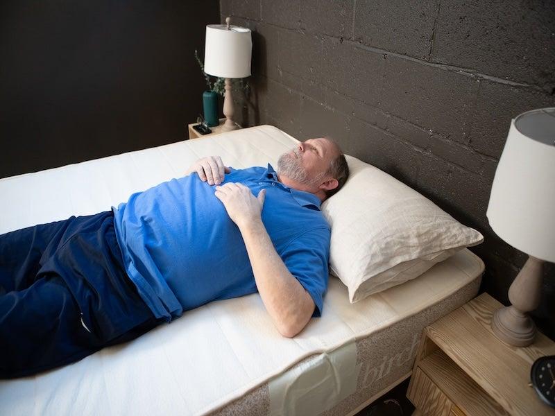 A man lies on his back on the Birch Natural mattress