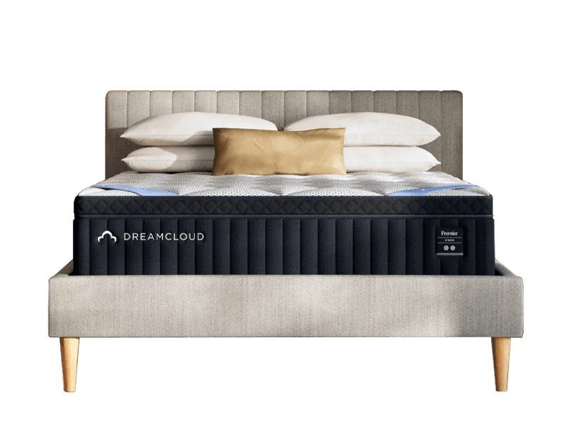 The DreamCloud Premier Hybrid mattress with pillows and a grey headboard