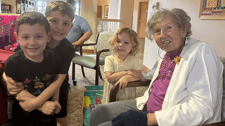 smiling grandmother with two young grandsons and granddaughter
