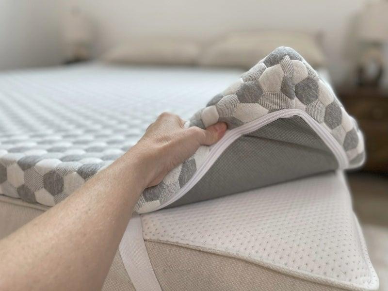 A person lifting the corner of the Layla mattress topper