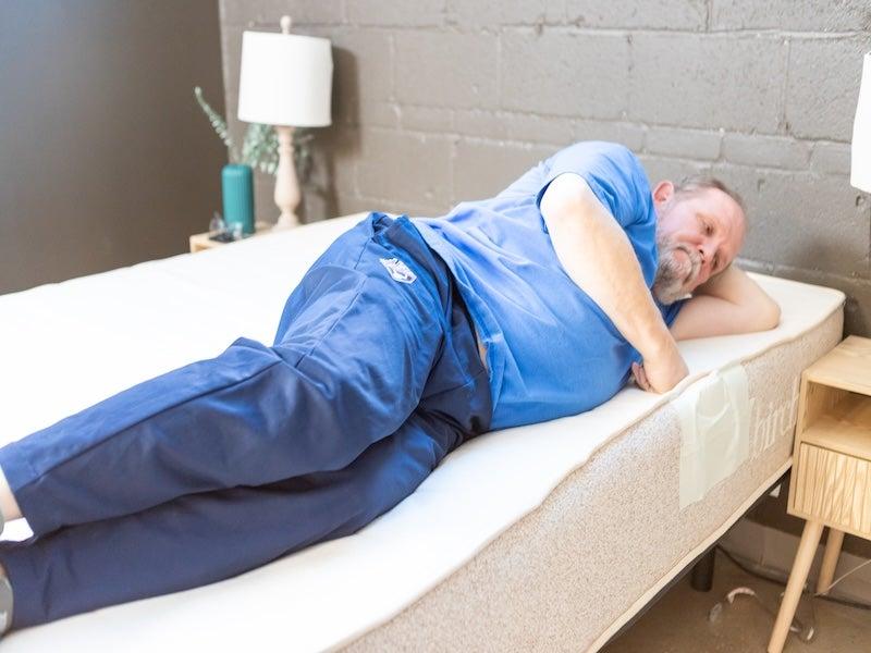 A man lies on his side on the Birch Natural mattress