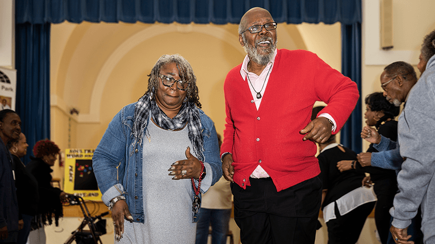 joyous dancing couple in a crowd at senior center dance