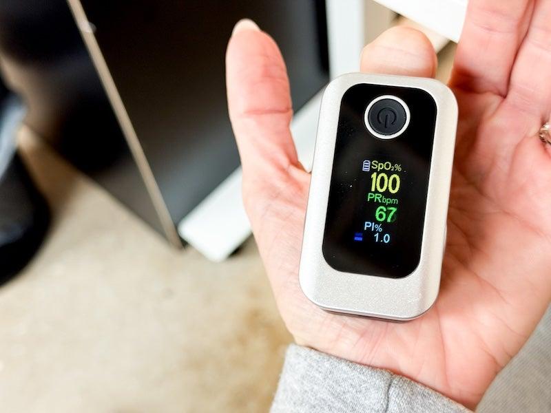 A woman wears the Oxiline XS Pro on her fingertip.