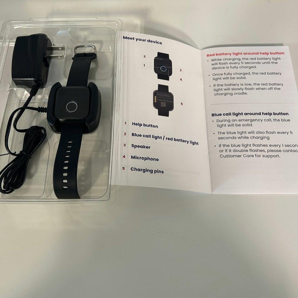 The MGMini Lite, a wristband medical alert system, in its packaging next to an open user manual showing instructions