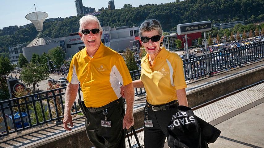 Two individuals wearing bright yellow shirts walking arm in arm.