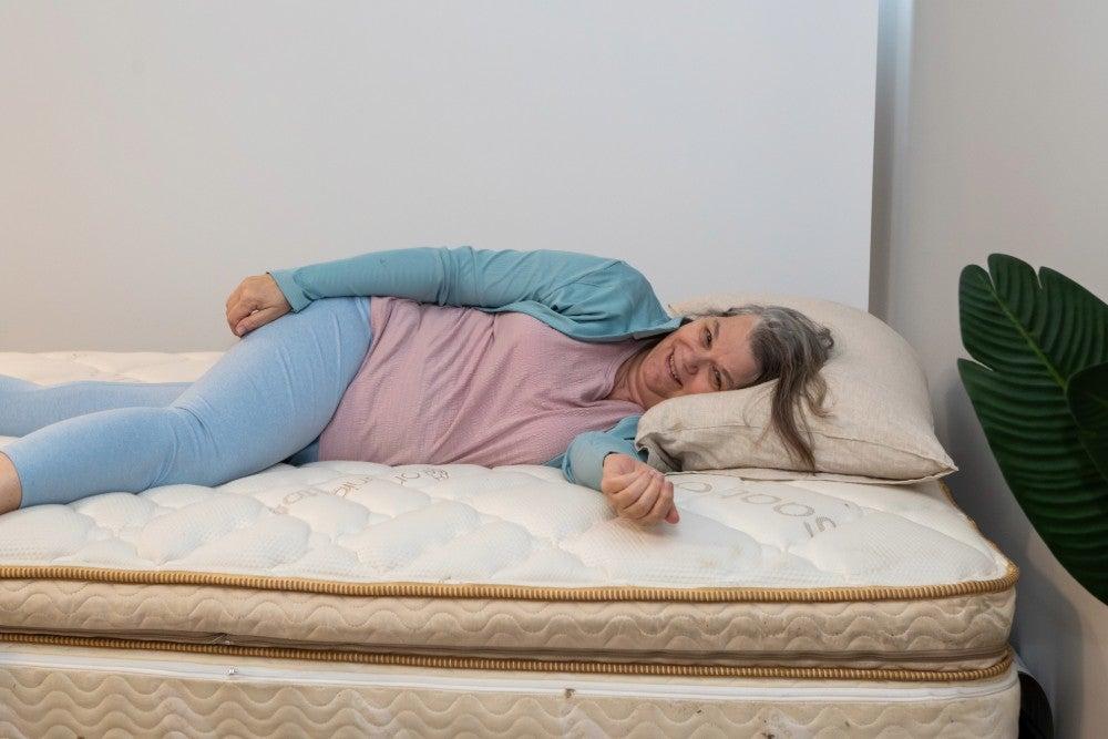 Older adult woman smiles while lying on her side in bed