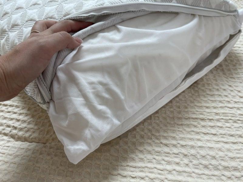 A hand opening the cover of the Brooklyn Bedding Talalay Latex Pillow to show its interior