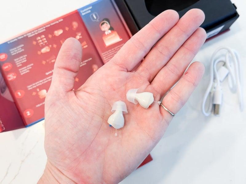 A pair of the Linner Saturn hearing aids in the palm of someone’s hand