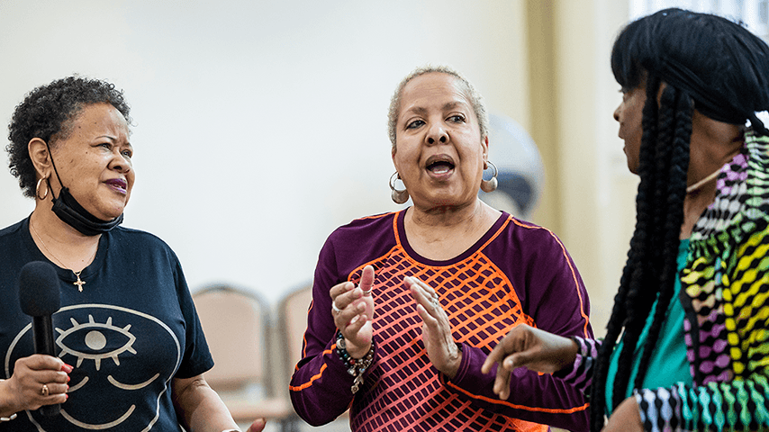 Three older women singing and clapping hands