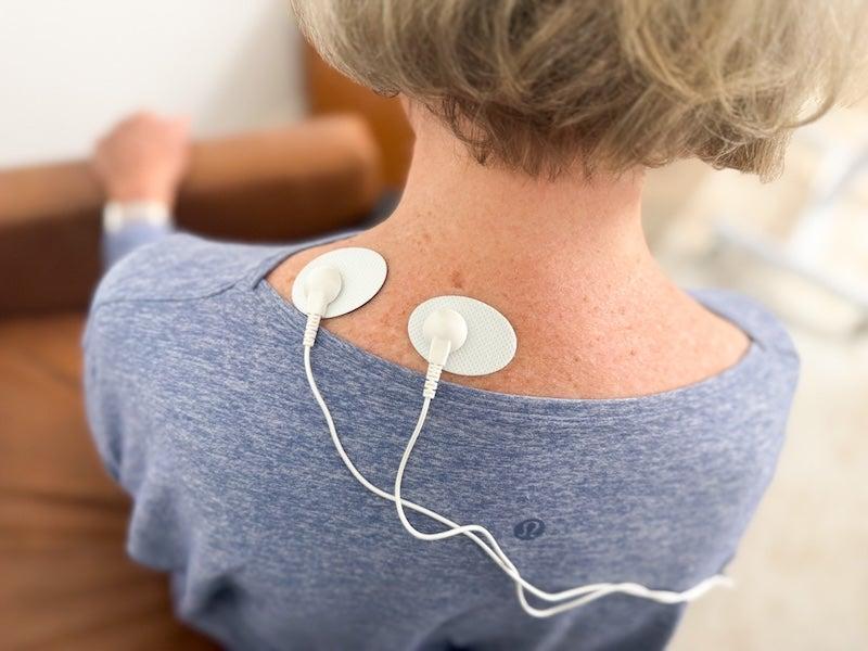 The electrodes of the Oxiline TENS XS Pro on the back of a woman’s neck