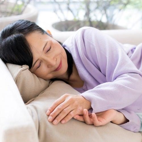 Woman sleeps on her side with a smile on her face