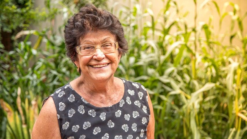smiling older woman standing in front of cornfield