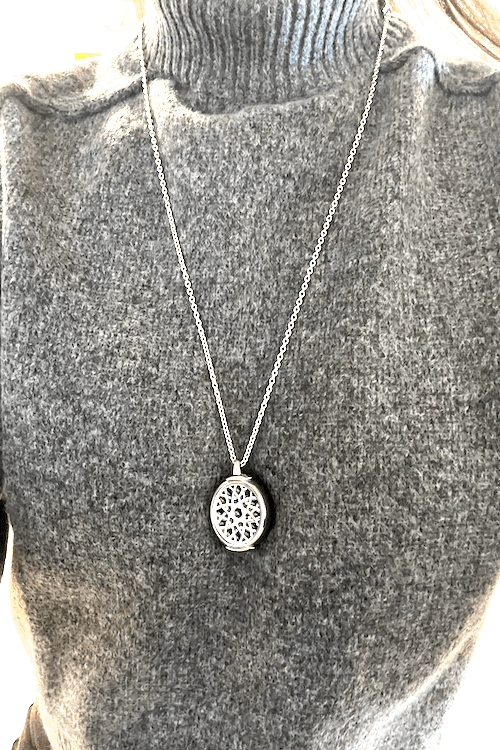 A woman wears the In-Home System’s help button on a silver chain.