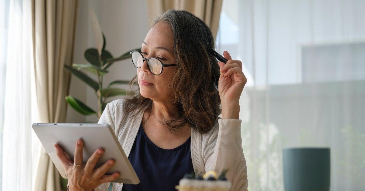 woman wearing glasses and looking at tablet