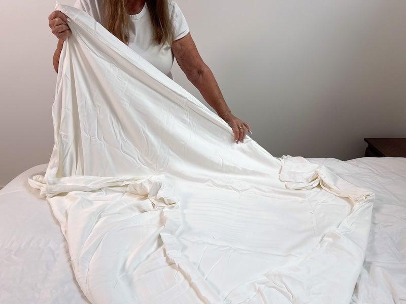 A woman spreads the Cozy Earth Bamboo Duvet Cover on a bed