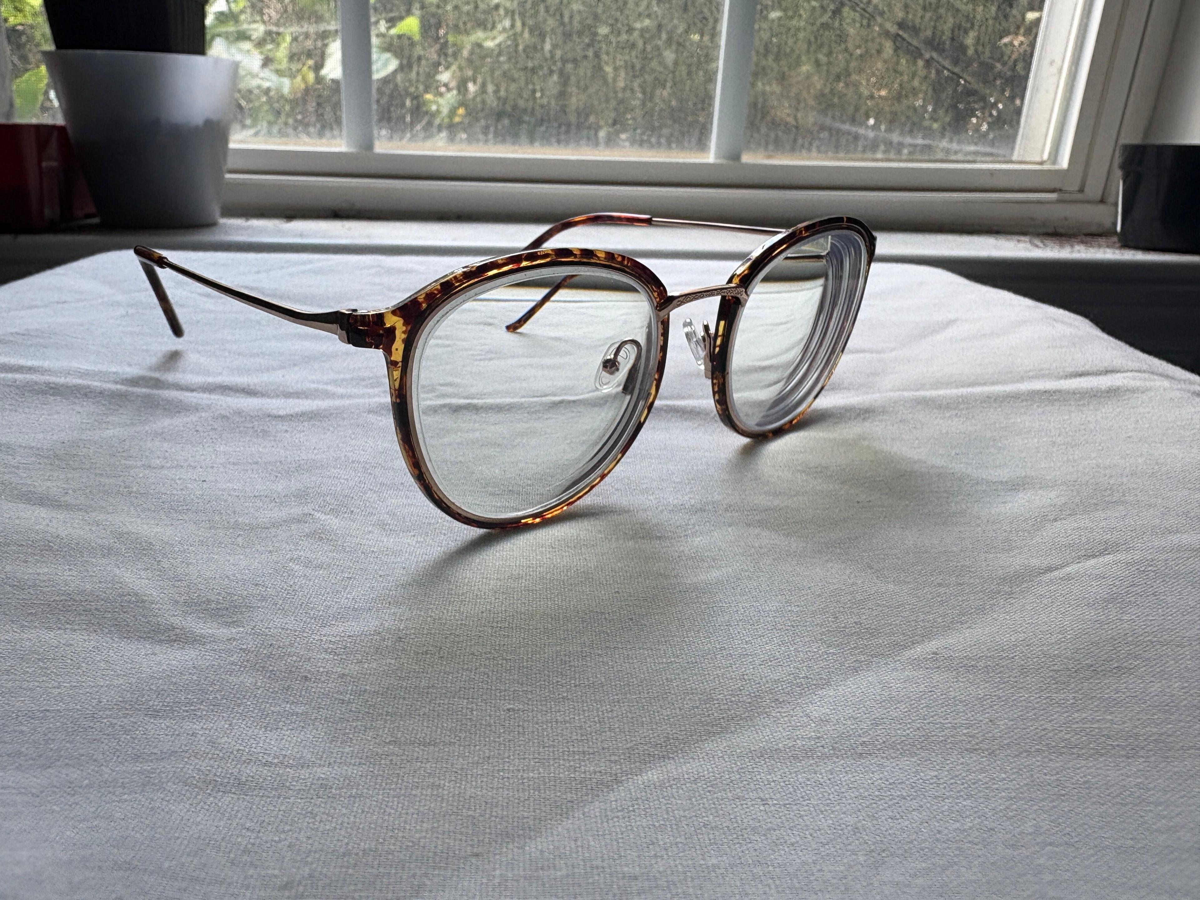 A pair of prescription eyeglasses sitting on a table in front of a window